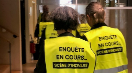 Des enquêteurs portant des gilets de haute visibilité affichant la phrase « Enquête en cours... Scène d'incivité » alors qu'ils traversent un couloir de bureau, indiquant une enquête en cours sur un incident civil.
