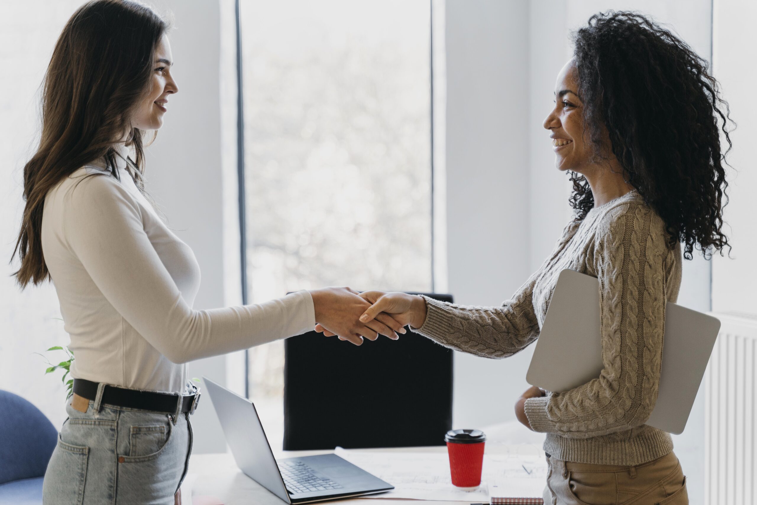 Deux femmes qui se serrent la main dans un bureau