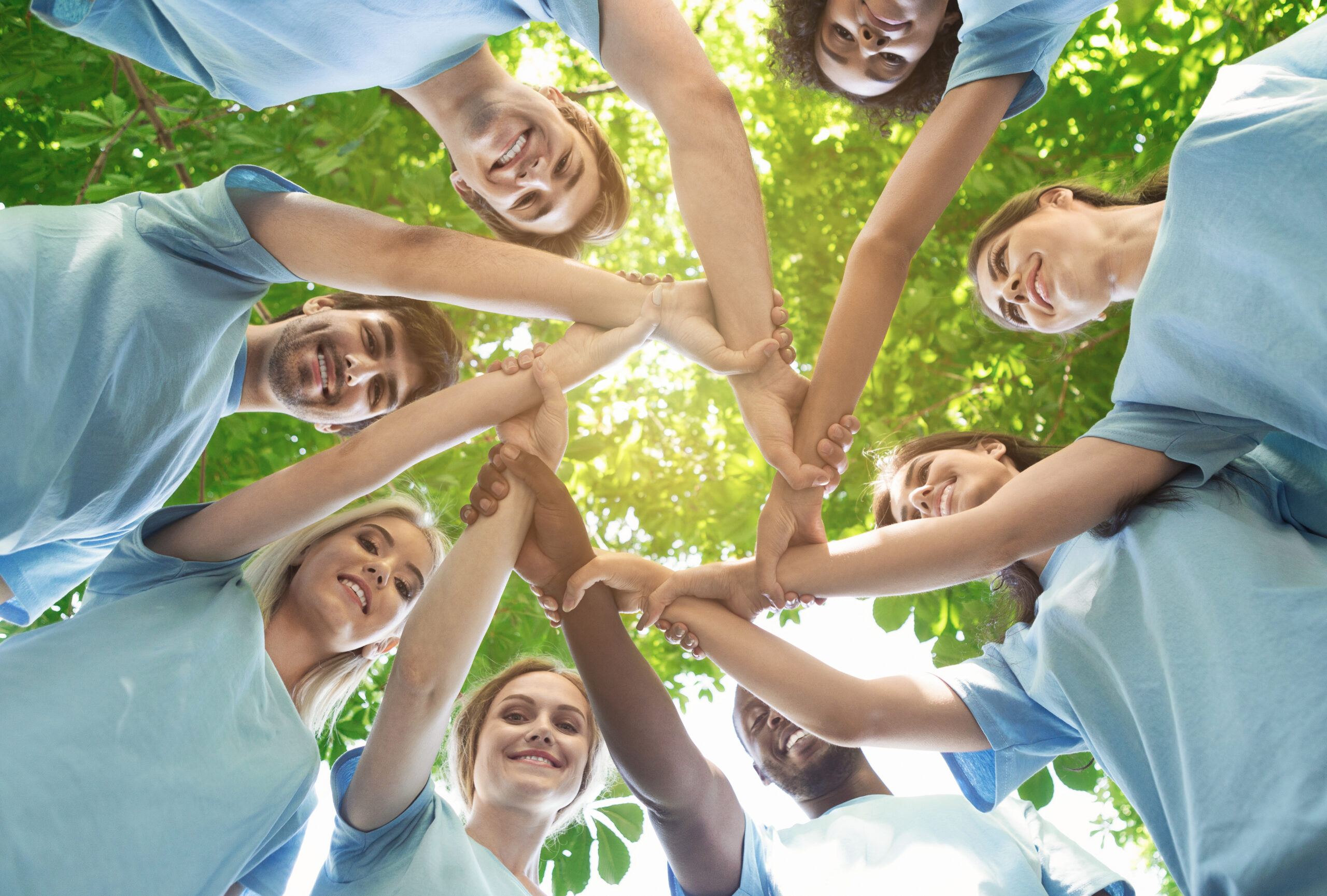 Concept de support. Des bénévoles heureux se tenant la main en cercle et souriant, exercice de team building, travail d'équipe et aide, vue d'en bas